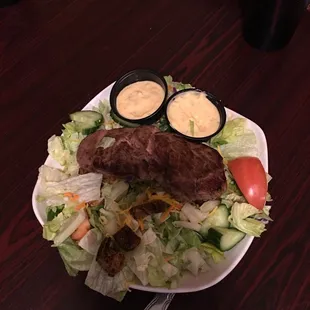 a plate of food with salad and dressings