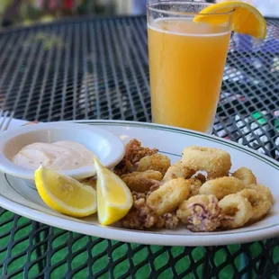 a plate of fried calamails and a glass of orange juice