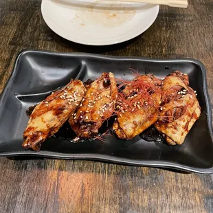 a plate of chicken wings and chopsticks