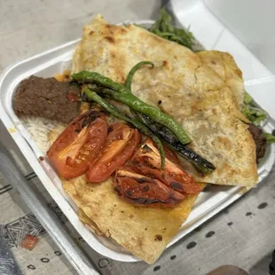 To go kabob plate with rice, fresh salad, crispy bread and chargrilled tomatoes and peppers