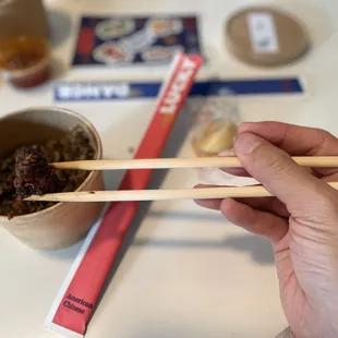 a person holding chopsticks over a bowl of food