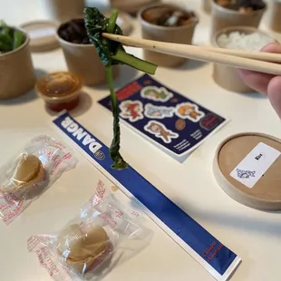 a person holding chopsticks over a table with food