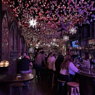 people sitting at a bar with lots of decorations hanging from the ceiling