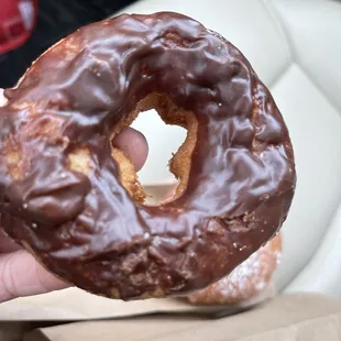 a hand holding a chocolate donut