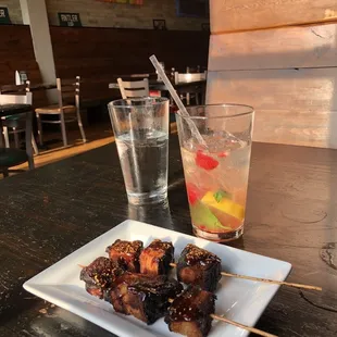 a plate of skewered food and a glass of water