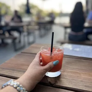 a person holding a drink on a table