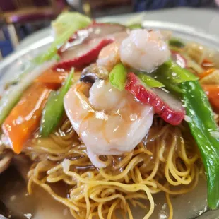 a plate of noodles with shrimp and vegetables