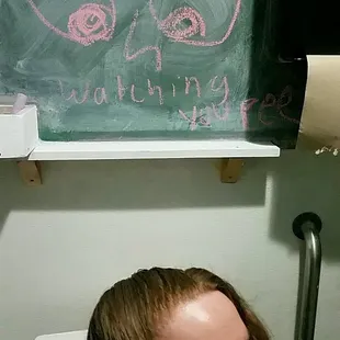 a man in a bathroom with a chalkboard on the wall