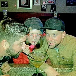 three men sitting at a table drinking a drink