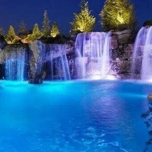 a pool with a waterfall at night