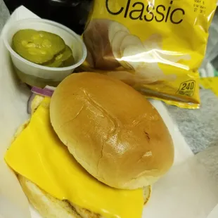 Grilled chicken s andwhich with pickles, onions and a side of Lays chips.