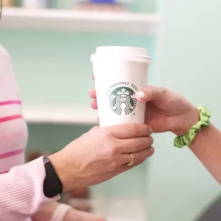 a starbucks cup being handed by a woman