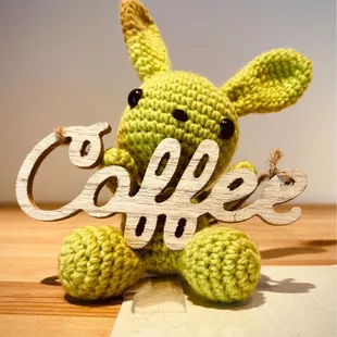 a crocheted bunny holding a coffee sign
