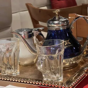 a silver tray with a silver teapot and glasses on it