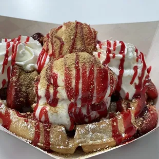 strawberry cheesecake ice cream with strawberries, strawberry syrup and graham cracker dust