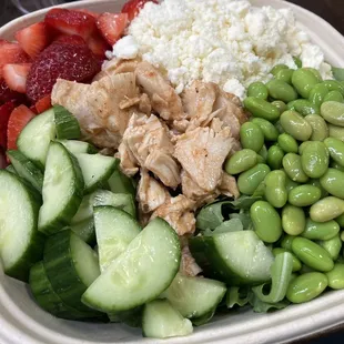 a bowl of rice, cucumbers, strawberries, and chicken
