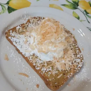 a piece of toast with whipped cream and toasted coconut flakes