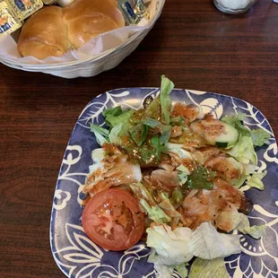 Side salad with house dressing and bread rolls.