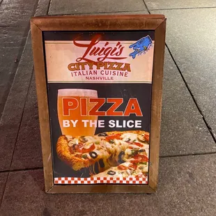 a sign for pizza by the slice