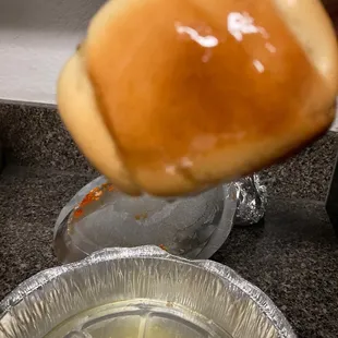 a hand dipping a hot dog bun