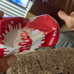 a hand holding a can of coke
