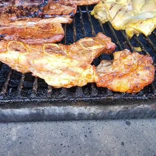a variety of meats cooking on a grill