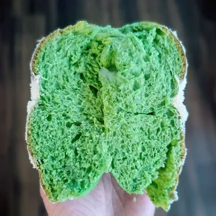 Pandan macapuno (coconut gelle) ensaymada (sweet bread) with butter and sugar on top sliced down the mid.