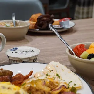 a breakfast of eggs, sausages, fruit, and coffee