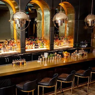 a row of bar stools in front of a row of liquor bottles