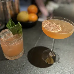 two cocktails sitting on a bar