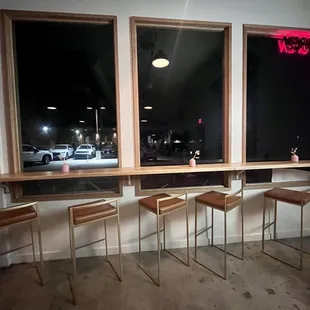 a row of bar stools in front of a window