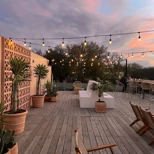 a deck with chairs, tables, and potted plants