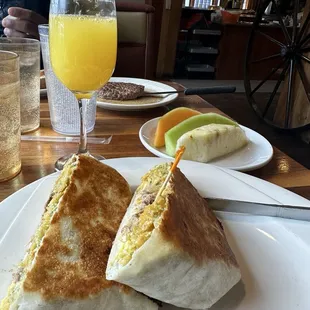Chilaquiles Crunch wrap, mimosa, fruit, and chopped steak, homemade fries, scrambled eggs with cheese and toast!