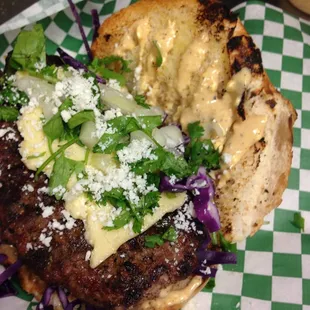 Habanero Cilantro Lime Burger with thick cut  Menonita, Cilantro, Green Onion, Cotija,  and Eloté Sauce on a toasted Bolillo Roll.