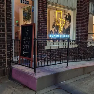 a neon sign in front of a brick building