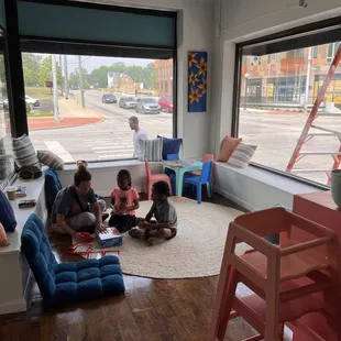 a group of children sitting on the floor in front of a window