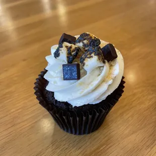 a cupcake with white frosting and chocolate pieces