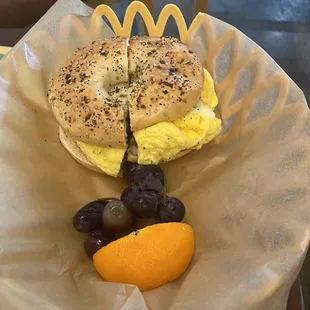 a bagel sandwich with egg and grapes