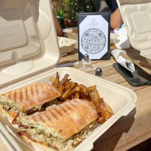 a sandwich and fries in a styrofoam container