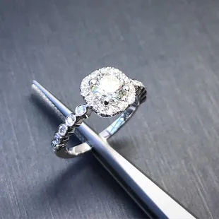 Custom cushion halo engagement ring, with bezel set round diamonds on band