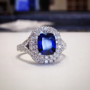 Cushion Cut Sapphire set into cushion shaped double diamond pave halo ring.
