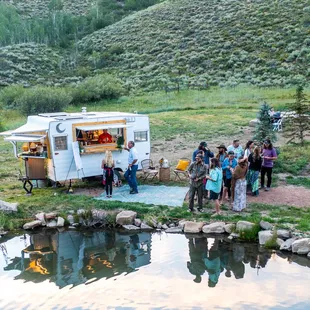 a group of people standing around a camper