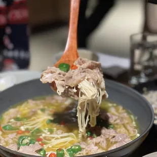 a person holding a spoon full of noodles