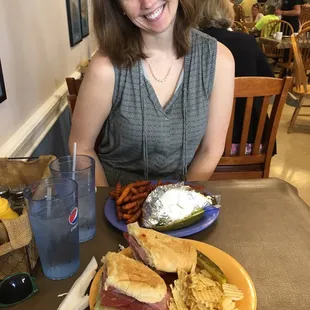 a woman sitting at a table with a sandwich and chips