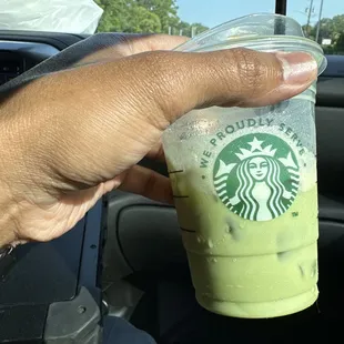 a hand holding a cup of green tea