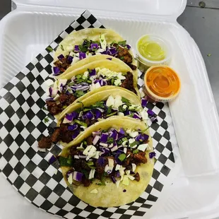three tacos on a checkered tray