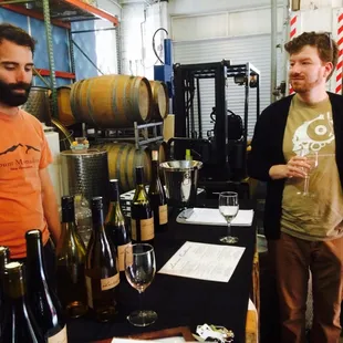 two men standing in front of wine barrels