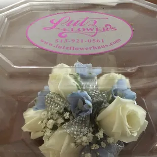 White sweetheart roses with blue delphiniums and a silver ribbon.