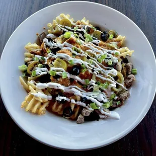 a plate of pasta with cheese and black olives