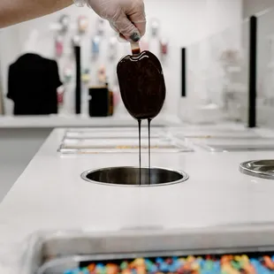 a person dipping a chocolate bar into a sink